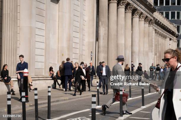 City employees sit and walk in spring sunshine beneath the high walls of the Bank of England on Threadneedle Street in the City of London, the...