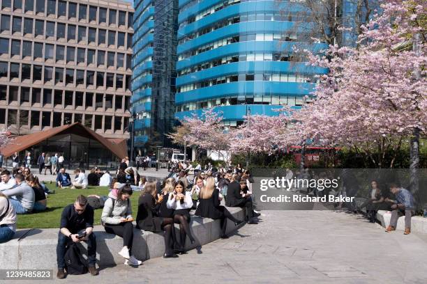 City office employees enjoy warm sunshine beneath spring cherry blossom in Aldgate Square in the City of London, the capital's financial district, on...