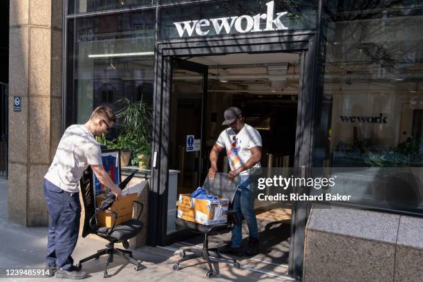Two employees in the financial industry push their office chairs and some belongings into new a workplace at WeWork in the City of London, the...