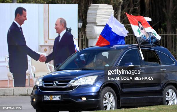 Syrians wave flag of Russia and a portrait of President Bashar al-Assad during a rally in support of Russia in the Syrian capital Damascus, on March...