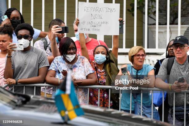 Woman holds a sign in protest as she waits for the arrival of Britain's Prince William and Catherine, Duchess of Cambridge, on the seventh day of...