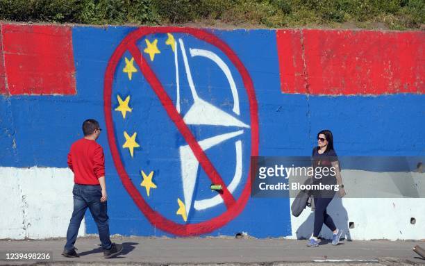 Pedestrians pass anti-European Union and NATO graffiti on a street in Belgrade, Serbia, on Friday, March 25, 2022. Serbia, which holds presidential...
