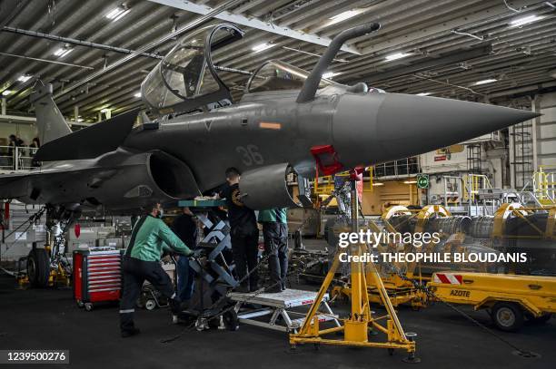 Mechanics work on a Rafale jet, in the hangar of the Charles-de-Gaulle aircraft carrier, on March 25 during military exercises on board the French...