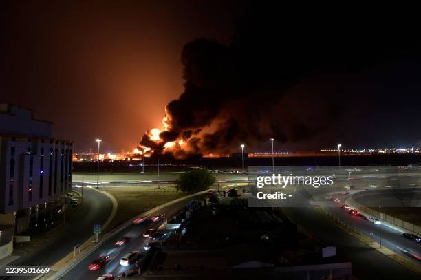 Cars drive on the roads as smoke and flames rise from a Saudi Aramco oil facility in Saudi Arabia's Red Sea coastal city of Jeddah, on March 25...