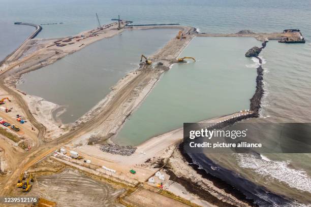 March 2022, Schleswig-Holstein, Fehmarn: Construction vehicles stand on the Baltic Sea coast during the construction of the Baltic Sea tunnel between...