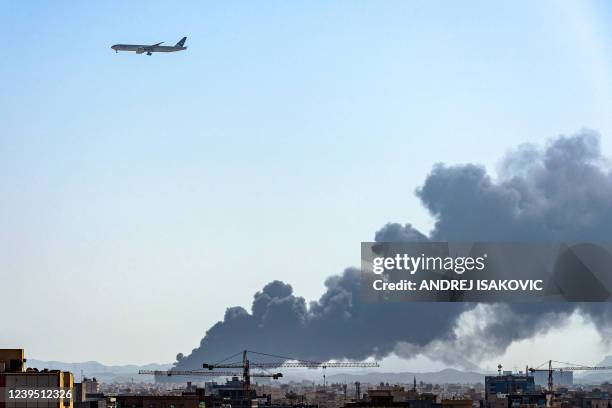 Pakistan International Airlines aircraft flies above as smoke rises from a Saudi Aramco oil facility in Saudi Arabia's Red Sea coastal city of...