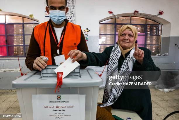 Palestinian woman shows her ink-stained finger as she casts her ballot while voting in the Palestinian local elections in the city of Hebron in the...