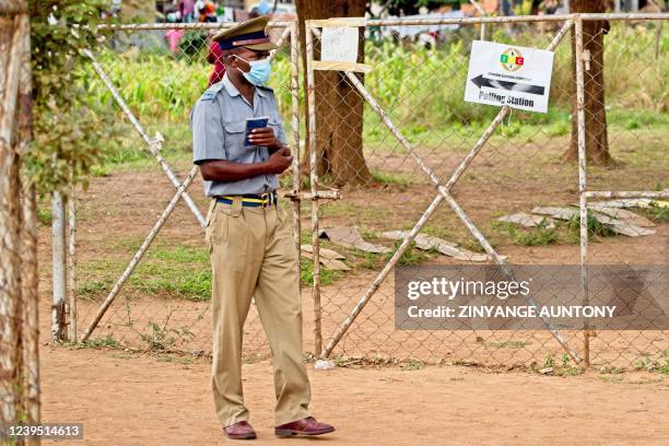 Police officer keep an eye on voters queueing at a polling station during a by-election on March 26, 2022 in Amaveni township, Kwekwe. - Zimbabweans...