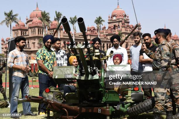 Students stand next to an anti-aircraft gun displayed during an exhibition of defence equipment by the Indian Army at Khalsa college in Amritsar on...