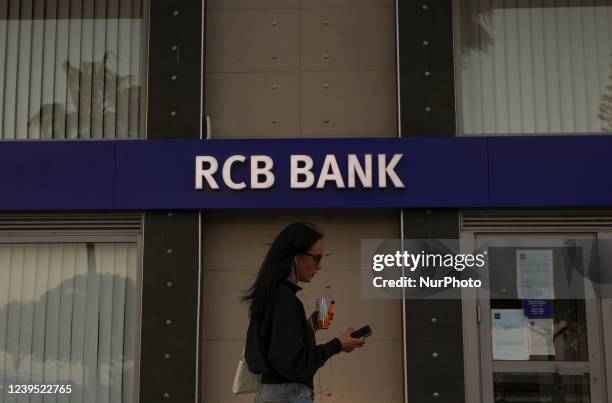 Woman uses her cell phone as she walks outside a branch of the RCB bank, a Russian commercial bank, in the Mediterranean port of Limassol. Cyprus,...