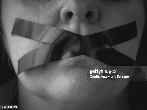 portrait of a woman with an x of adhesive tape covering her mouth - extremism photos et images de collection