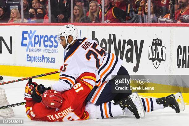 Darnell Nurse of the Edmonton Oilers checks Matthew Tkachuk of the Calgary Flames during the third period an NHL game at Scotiabank Saddledome on...