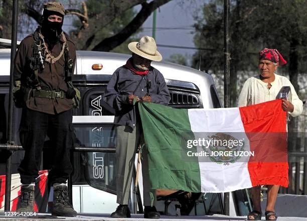 Subcommander Marcos stands next to two farmers who hold the Mexican flag during a rally in front of the Legislative Palace in Mexico City 22 March...