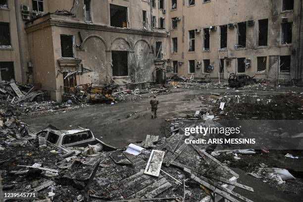 Ukranian serviceman walks between rubble of the destroyed regional headquarters of kharkiv on March 27, 2022. - France's President Emmanuel Macron...