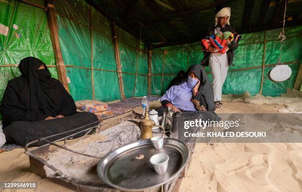 An Egyptian bedouin family sit around a fire pit at their home in al-Rawda village near el-Arish city, in the northern Sinai Peninsula, on March 20,...