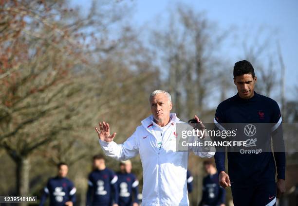 France's national football team head coach Didier Deschamps gestures next to defender Raphael Varane as they arrive for a training session in...