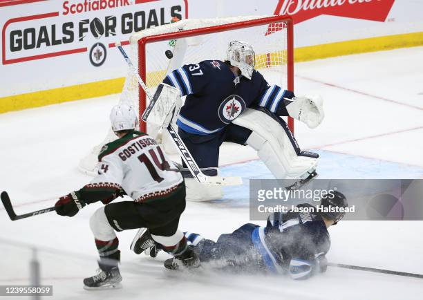 Shayne Gostisbehere of the Arizona Coyotes hits the post past Connor Hellebuyck of the Winnipeg Jets in overtime during a game on March 27, 2022 at...