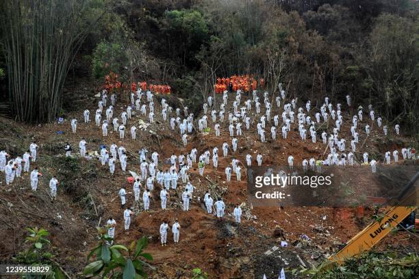 This photo taken on March 27, 2022 shows rescuers standing in a silent tribute for victims at the site of the China Eastern Airlines plane crash in...