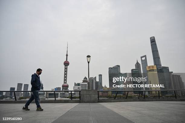 Man walks on the promenade on the Bund along the Huangpu River as buildings are seen in Pudong district that is in lockdown as a measure against the...