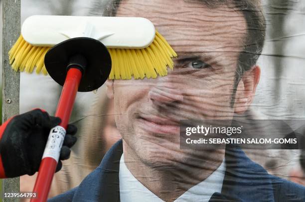 An employee of a display company pastes the official campaign poster of French President and centrist La Republique en Marche party candidate for...