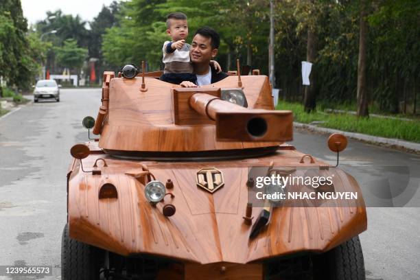 Truong Van Dao and his son ride in a wooden tank made from the conversion of an old minibus in a residential area in Bac Ninh province on March 28,...