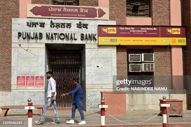 People walk past a closed branch of Punjab National Bank during a nationwide general strike against the policies of the central government, in...