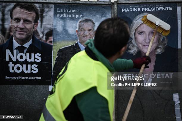 An employee of a display company placards presidential candidates' official campaign posters French President of the Emmanuel Macron centrist La...