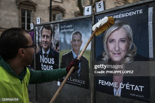 An employee of a display company placards presidential candidates' official campaign posters French President of the Emmanuel Macron centrist La...