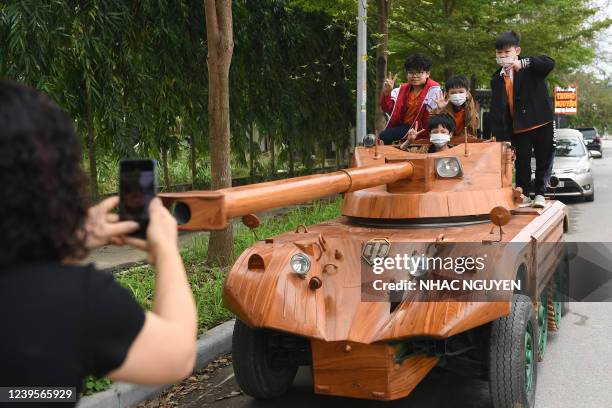 Children pose for photos on a wooden tank made from the conversion of an old minibus in a residential area in Bac Ninh province on March 28, 2022. -...