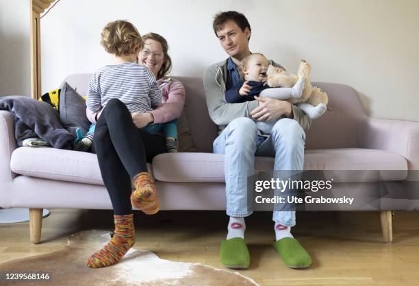 In this photo illustration a family with two siblings is sitting on a sofa in their livingroom on March 20, 2022 in Bonn, Germany.