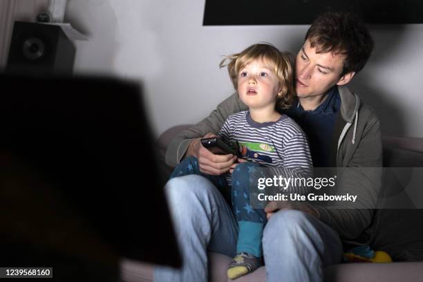 In this photo illustration a father and a child are sitting in front of a screen on March 20, 2022 in Bonn, Germany.