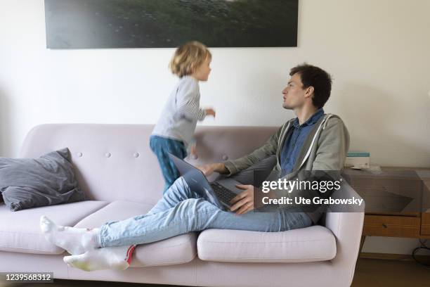 In this photo illustration a father with child is working on sofa on March 20, 2022 in Bonn, Germany.