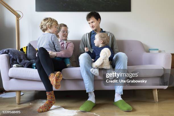 In this photo illustration a family with two siblings is sitting on a sofa in their livingroom on March 20, 2022 in Bonn, Germany.