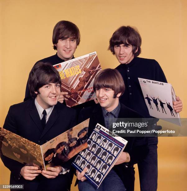 Studio portrait of The Beatles looking at some of their album covers, left to right, Paul McCartney, John Lennon, Ringo Starr and George Harrison,...