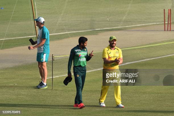 Pakistani captain Babar Azam and his Australia's counterpart Aaron Finch walk as they arrive for a practice session at the Gaddafi Cricket Stadium in...