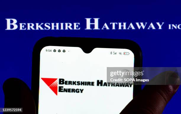 In this photo illustration, the Berkshire Hathaway Energy logo is displayed on a smartphone screen with a Berkshire Hathaway Inc. Logo in the...