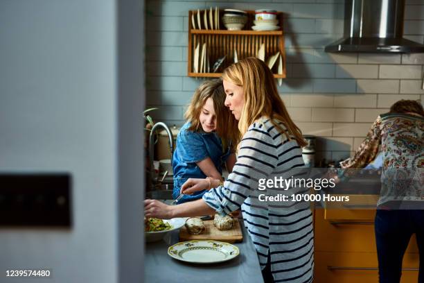 mother serving lunch with daughter in kitchen - woman diet indoor stock-fotos und bilder