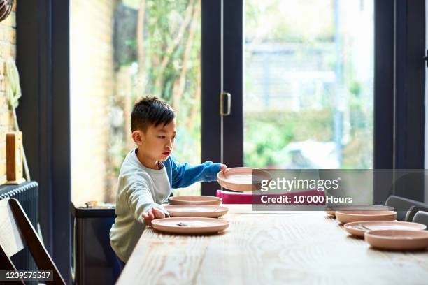 young boy setting table for lunch - arrangiare foto e immagini stock