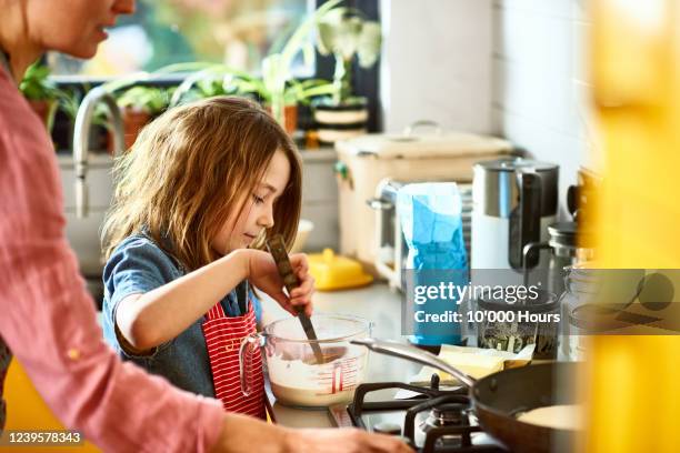 girl stirring pancake batter, in kitchen with mother - making pancakes stock pictures, royalty-free photos & images