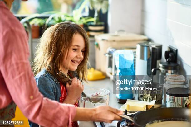 girl learning to make pancakes with mother - making pancakes stock pictures, royalty-free photos & images