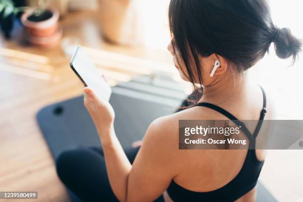 young woman practicing yoga and using smartphone at home - bluetooth headphones stock pictures, royalty-free photos & images