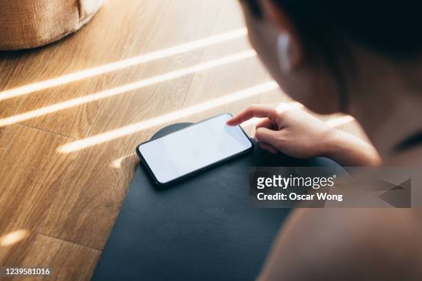 young woman practicing yoga and using smartphone at home - horizontal stock-fotos und bilder