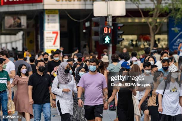 People are wearing face masks as a preventive measure against the spread of covid-19 while walking along Orchard Road, a famous shopping district in...