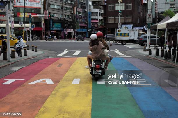 Local residents ride past a sign at Ximen district in Taipei on March 29, 2022.