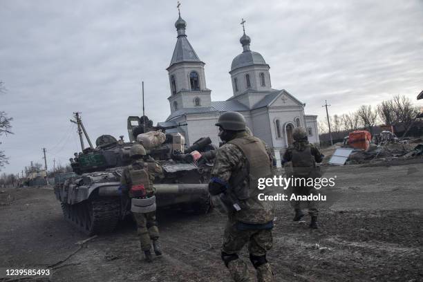 Ukrainian volunteer fighters take cover behind a military armored vehicle as they look for Russian soldiers in Lukâyanivka frontline, eastern of...