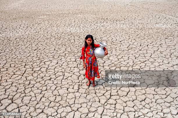 Gril walks into a deep cracks field after collecting drinking water from a pond near mangrove forest Sundarban in Satkhira, Bangladesh on March 27,...