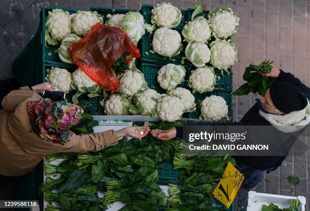 Woman buys spinach at a fruit and vegetable market on March 29, 2022 in Berlin. - Russia's invasion of Ukraine, has further piled on the price...