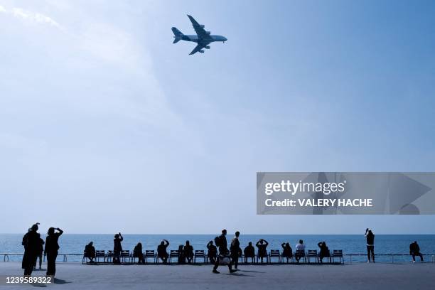 Members of the public look at an Airbus A380 flying along the "Promenade des Anglais" on the French riviera city of Nice during an airport test day,...