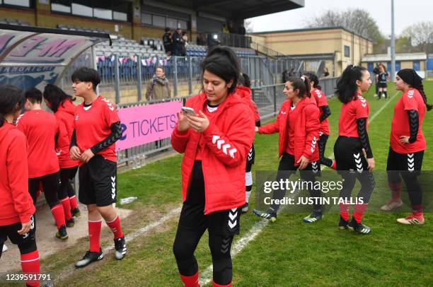 Afghan development squad team player looks at the her phone during the half time of the football match between Afghan development squad and Womens...