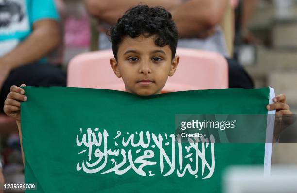 Young Saudi supporter lifts the national flag in the stands during the 2022 Qatar World Cup Asian Qualifiers football match between Saudi Arabia and...